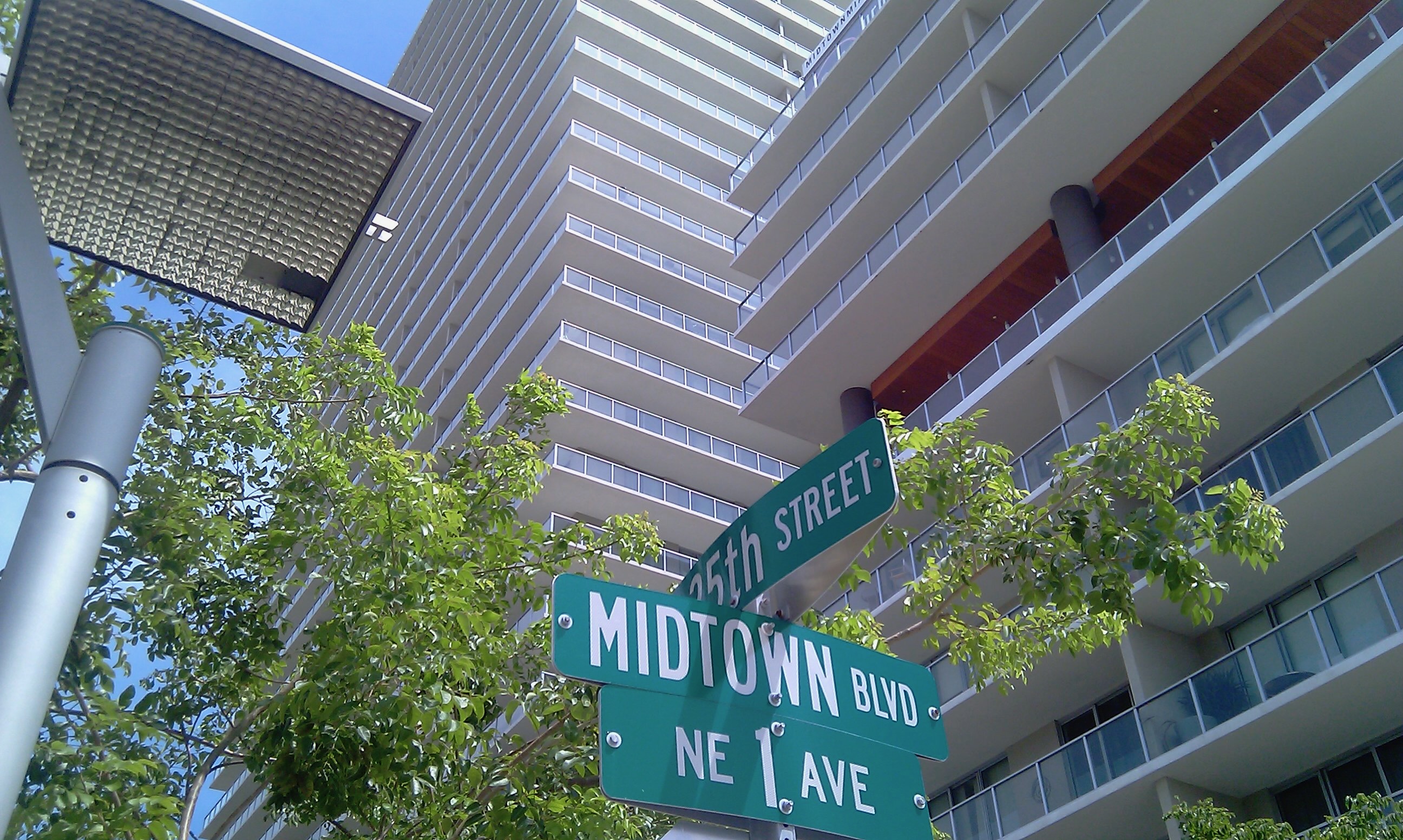 Midtown Miami street view with modern condominium tower and neighborhood signage