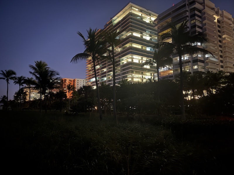 Bal Harbour luxury oceanfront towers illuminated at night viewed from the beach path
